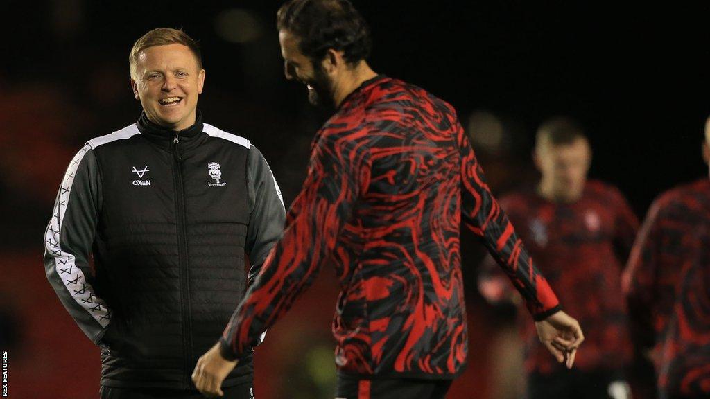 Interim Lincoln City boss Tom Shaw smiles while talking to one of his players