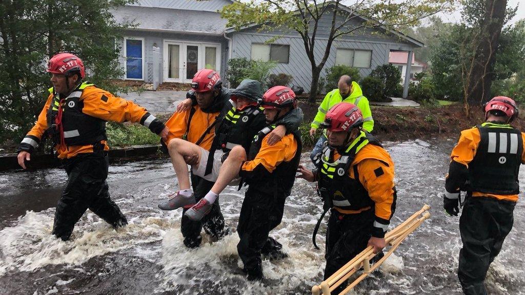 Rescue workers carry a man away from flooding in River Bend, North Carolina (14 September)