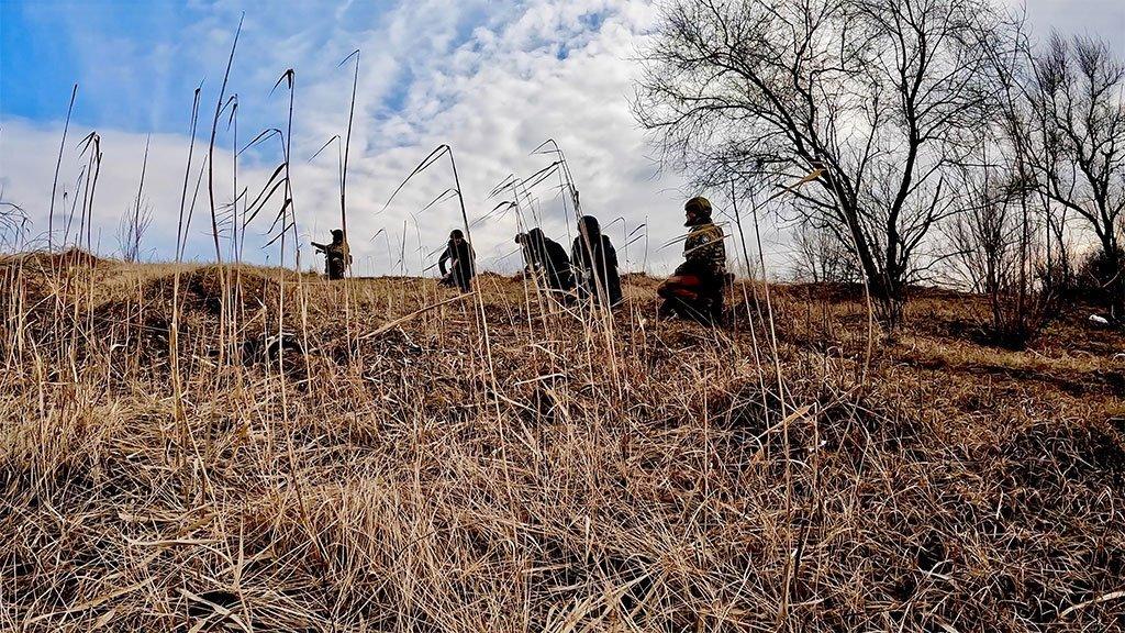 Soldiers move through the tall grass