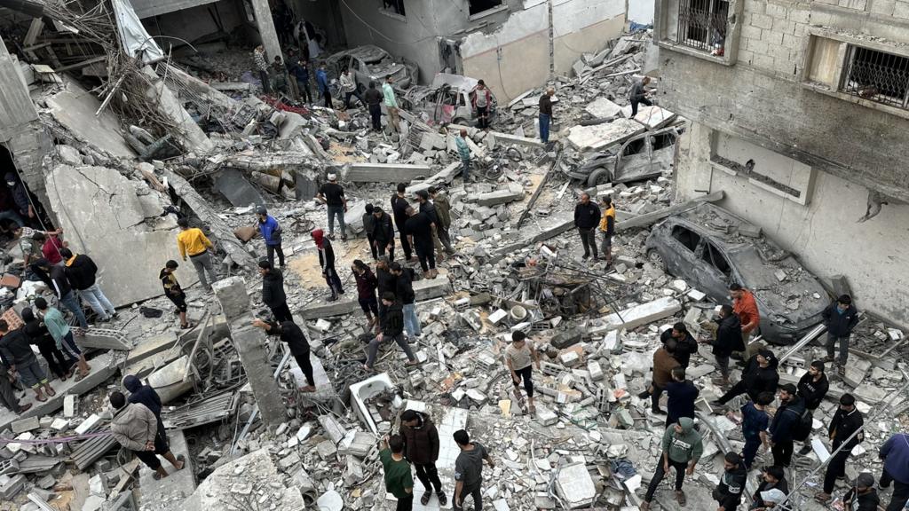 People walk through the rubble of a building destroyed in Gaza