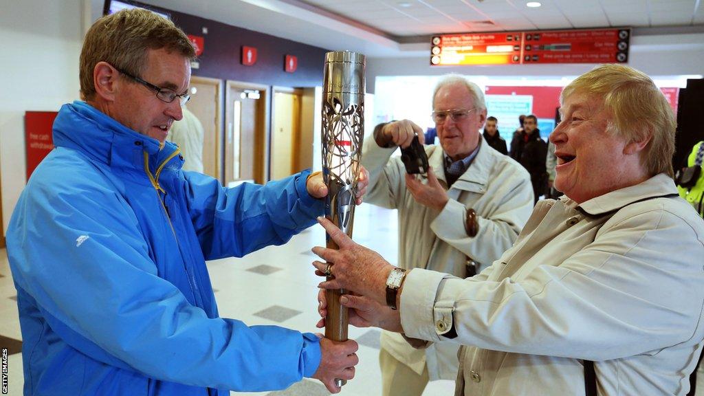 Chris Jenkins (L) hands over the baton ahead of the Glasgow 2014 Commonwealth Games