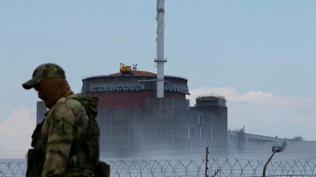 A serviceman with a Russian flag on his uniform stands guard near the Zaporizhzhia Nuclear Power Plant