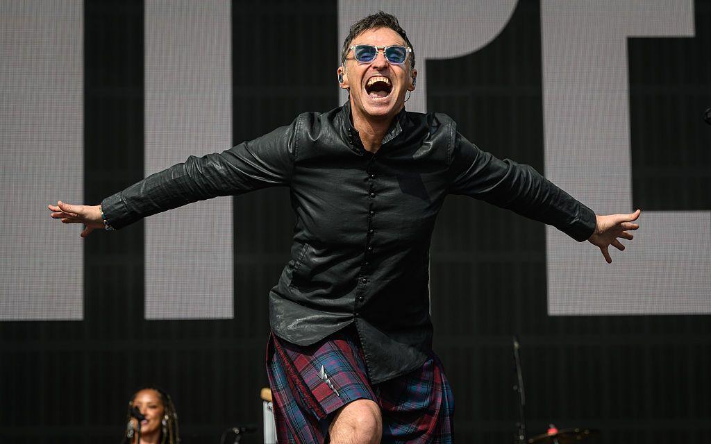 Marti Pellow performs onstage during Radio 2 In The Park at Hylands Park in Chelmsford - he is leading forward to the crowd, arms stretched wide behind him, a roar of a smile on his face, wearing a dark red and blue kilt with lightning bolt kilt pin and a leather shirt.