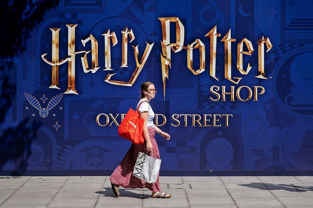 A woman carrying shopping bags passes a hoarding over what will become the new Harry Potter shop on Oxford Street.