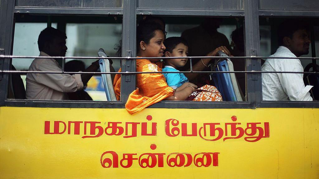 A yellow and black coloured bus in southern India's Chennai city, with a woman in sari seen with a child in her lap