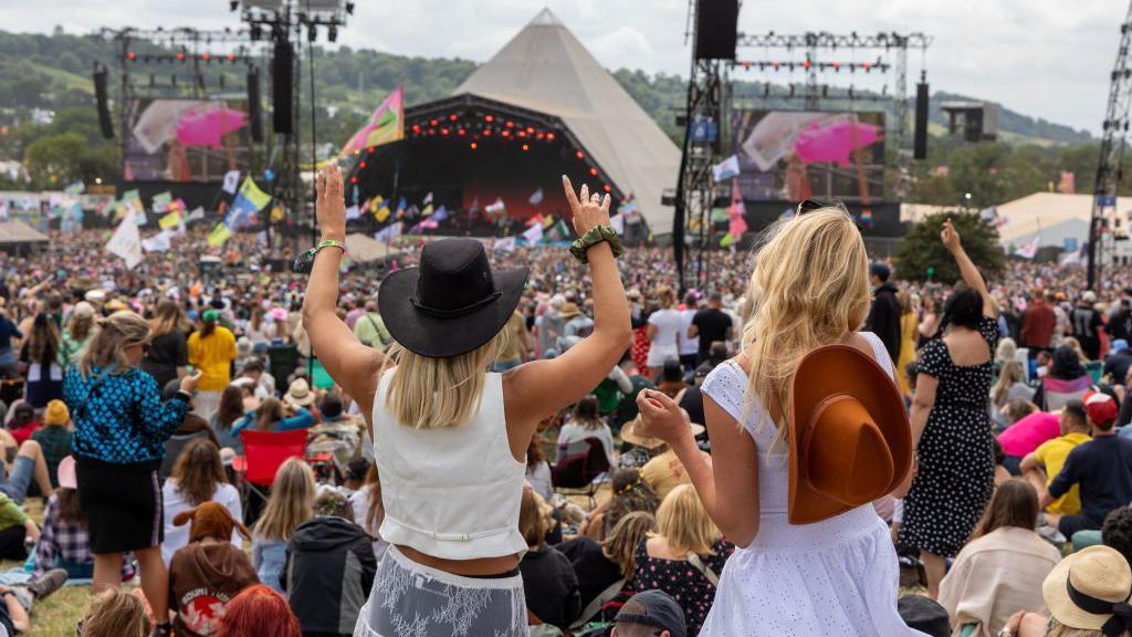 A crowd of people dancing in front of a stage at Glastonbury Festival