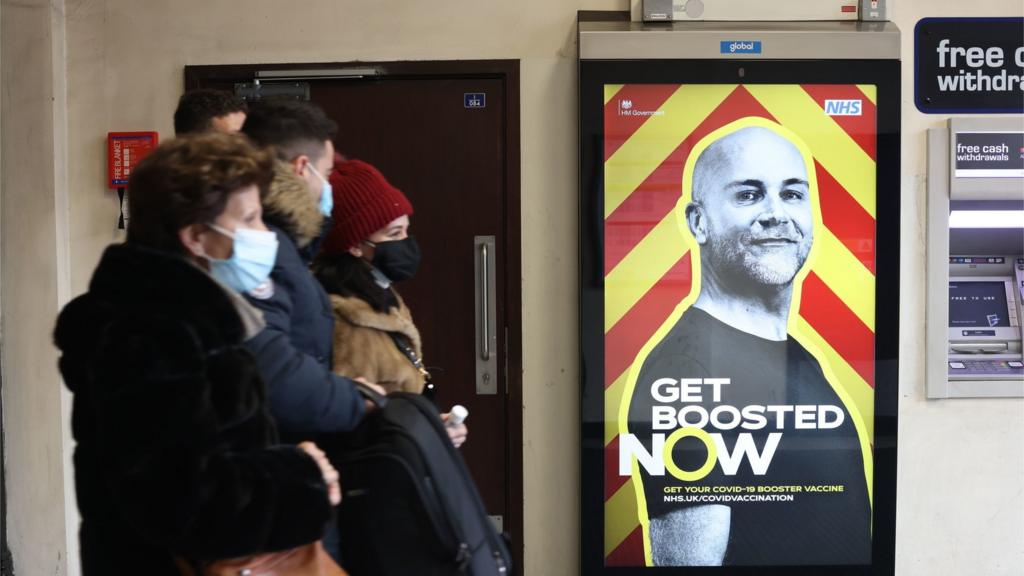 People in masks walk through a London underground station