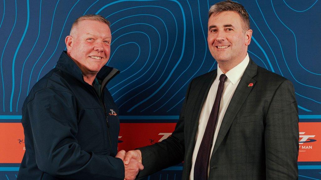 Gary Thompson and Tim Johnston shaking hands against a backdrop of TT branding