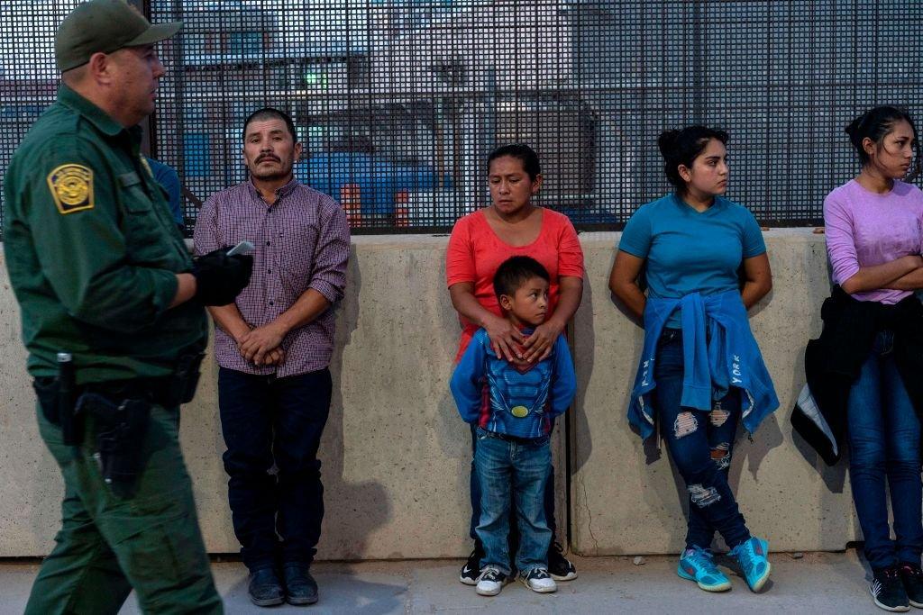 Migrants, mostly from Central America, wait to board a van which will take them to a processing center