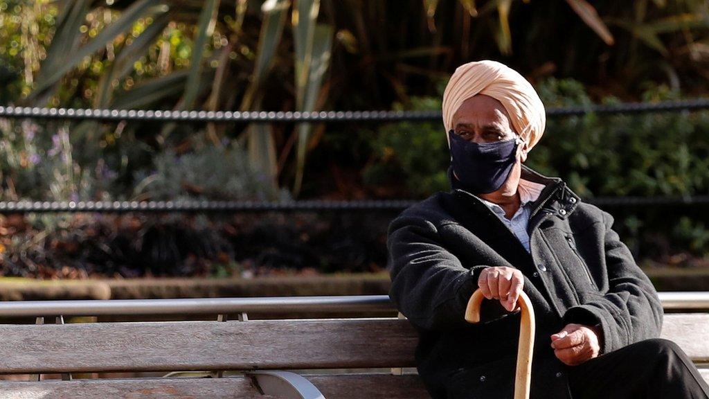 Elderly man sits on bench with walking stick