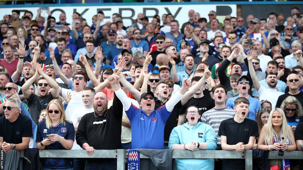 Carlisle United fans sing on the paddock at Brunton Park