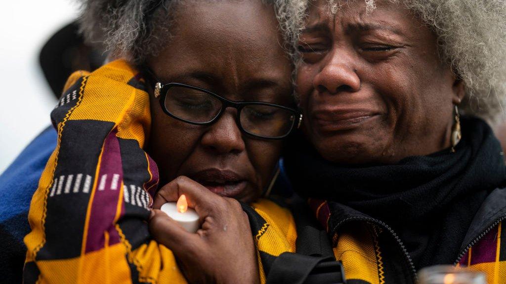 Two women crying at a vigil