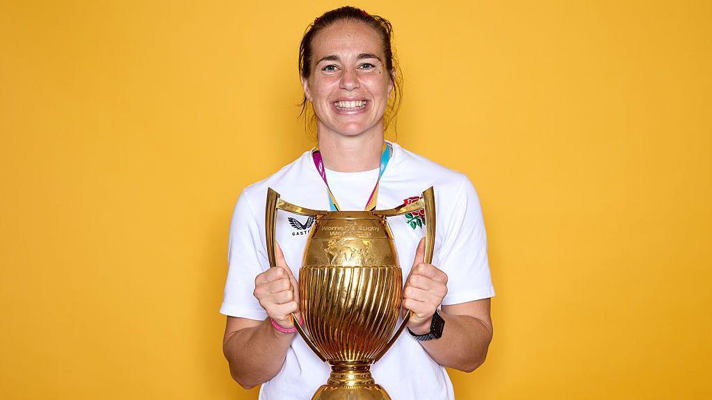 Emily Scarratt holding the World Cup trophy.
