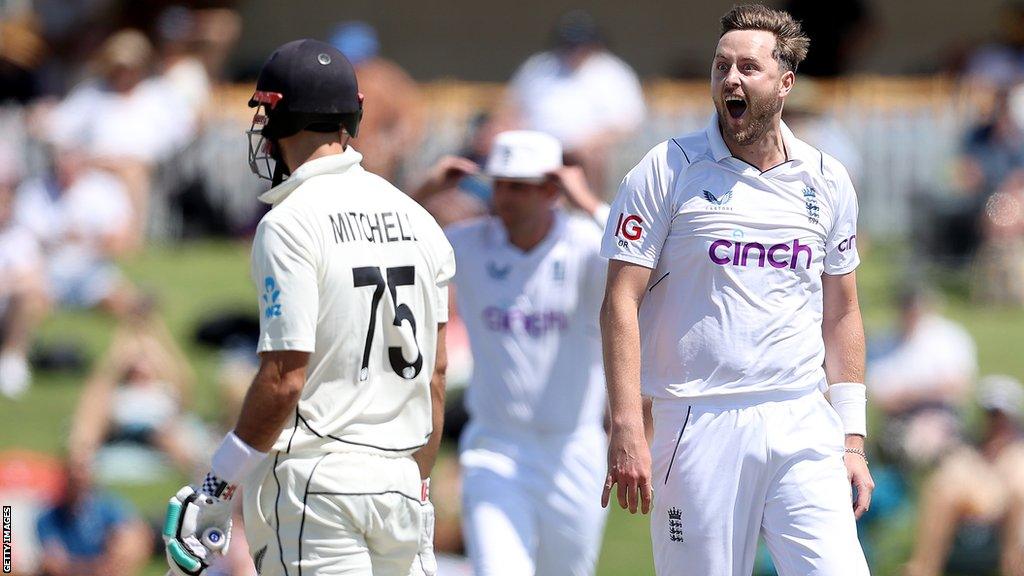 Ollie Robinson (right) celebrates dismissing Daryl Mitchell (left)