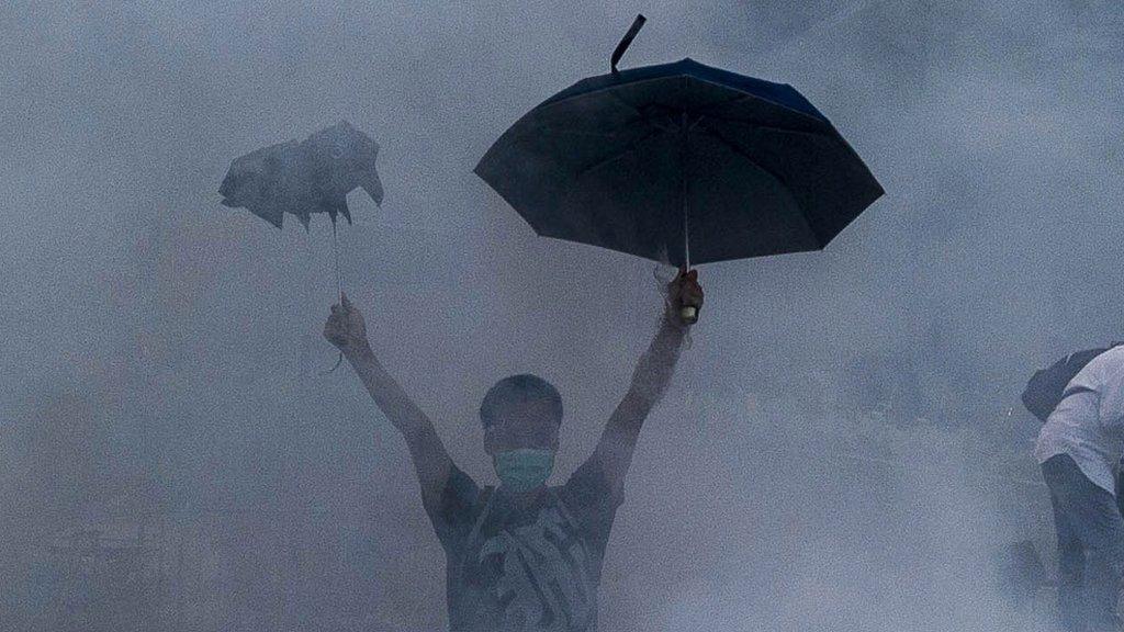 A pro-democracy demonstrator gestures after police fired tear gas towards protesters near the Hong Kong government headquarters on September 28, 2014