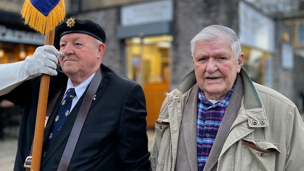 Arthur Oborne, right, in a pale green goal looking at the camera smiling, next to a man in a beret from the Royal British Legion