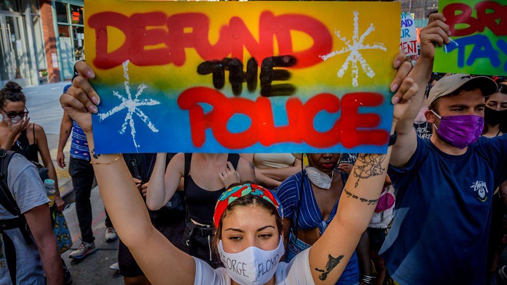 Protester with sign saying defund the police