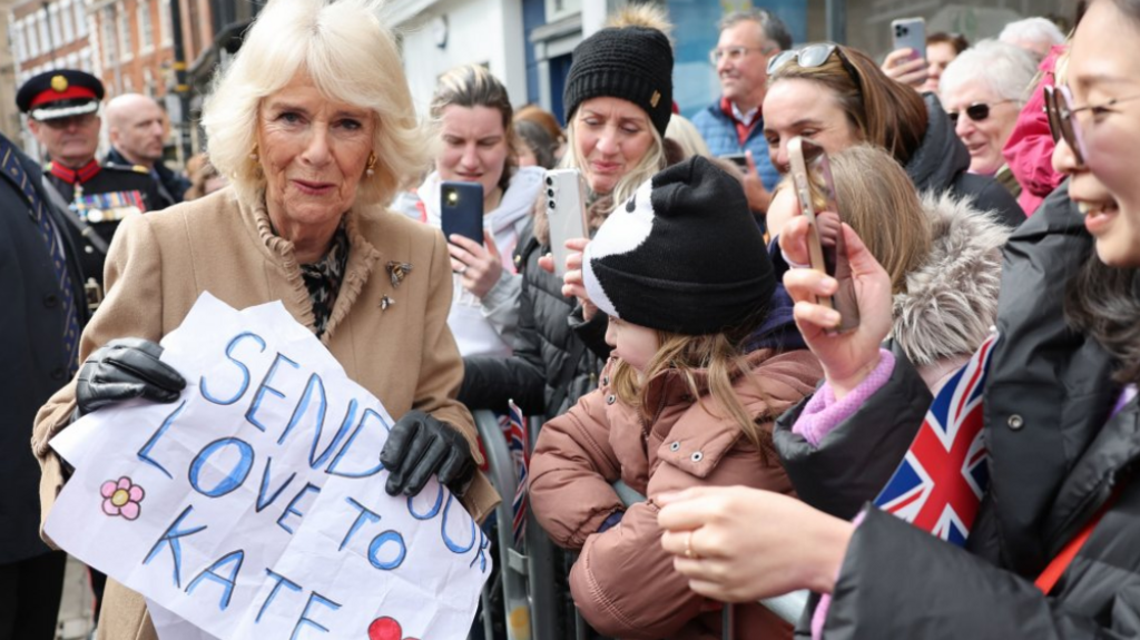 The Queen with a sign saying "send our love to Kate"