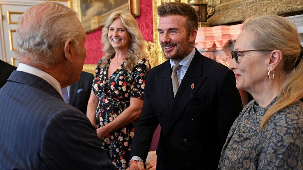 David Beckham shaking King Charles' hand.