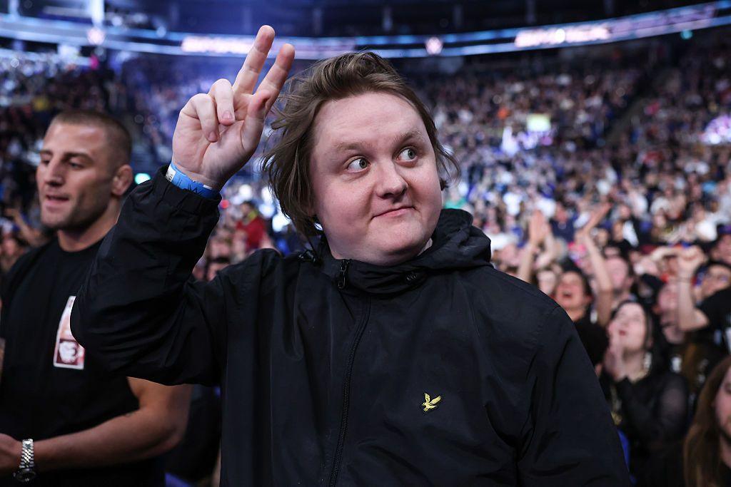 Lewis Capaldi gesturing to a crowd with one hand in the air