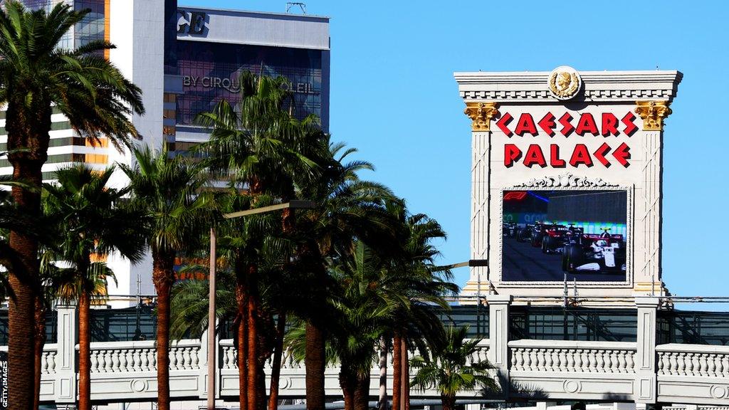 A big screen below Caesars Palace shows Formula 1 cars racing