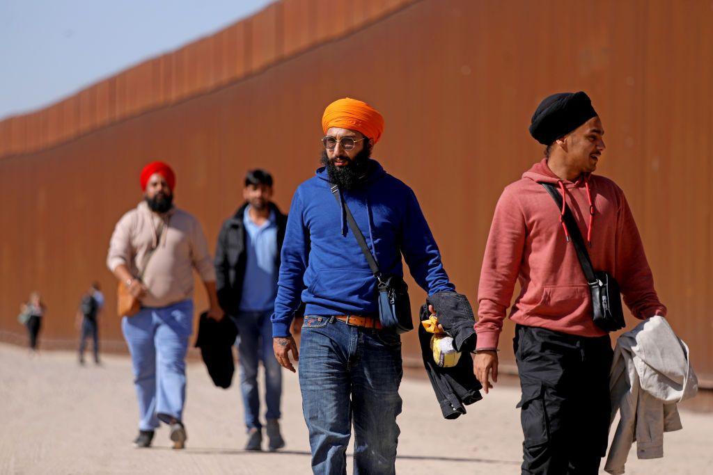 Immigrants from India walk along the border wall to turn themselves over to U.S Border Patrol agents along the U.S.-Mexico border on Thursday, May 11, 2023 in San Luis Colorado, Sonora.