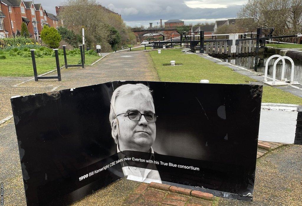 A panel displaying an image of Bill Kenwright is seen beside the canal where it was found