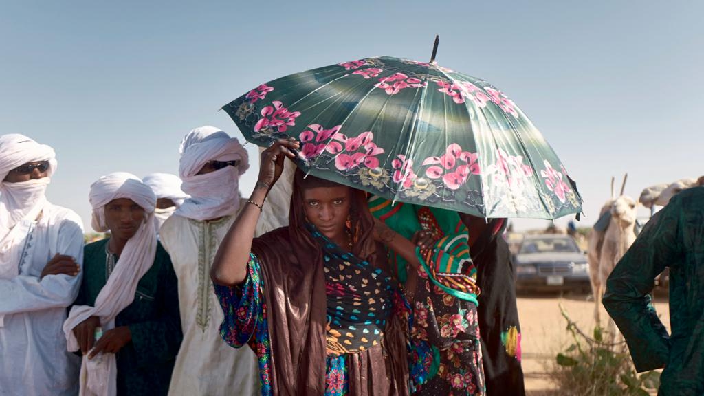 A woman shelters from the sun while she watches a camel race in northern Niger - 2021