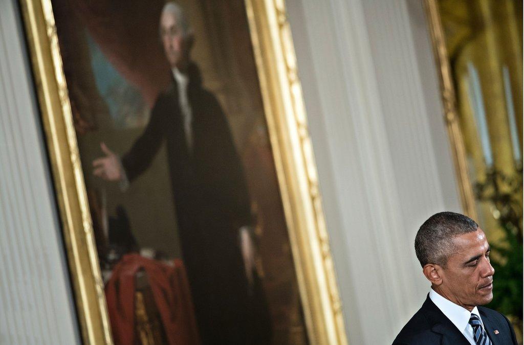 President Obama standing before a portrait of George Washington