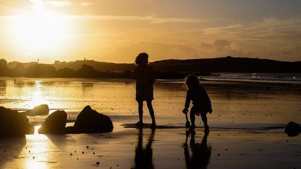 Two children playing on a beach at sunset