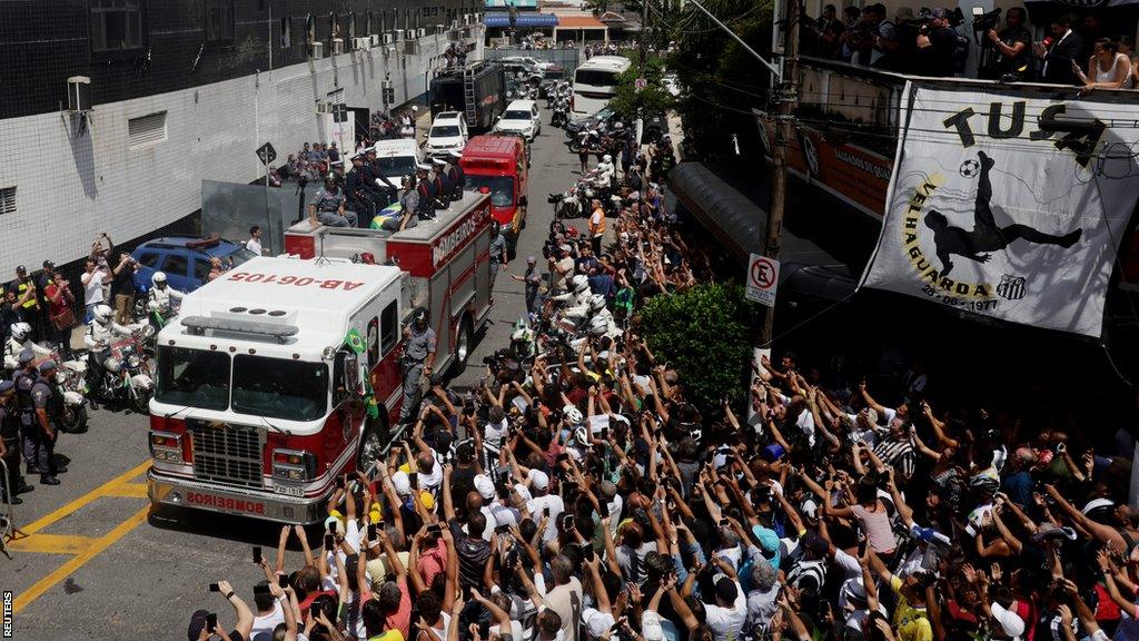 Pele's coffin is escorted on a fire truck through Santos where fans are lining the streets