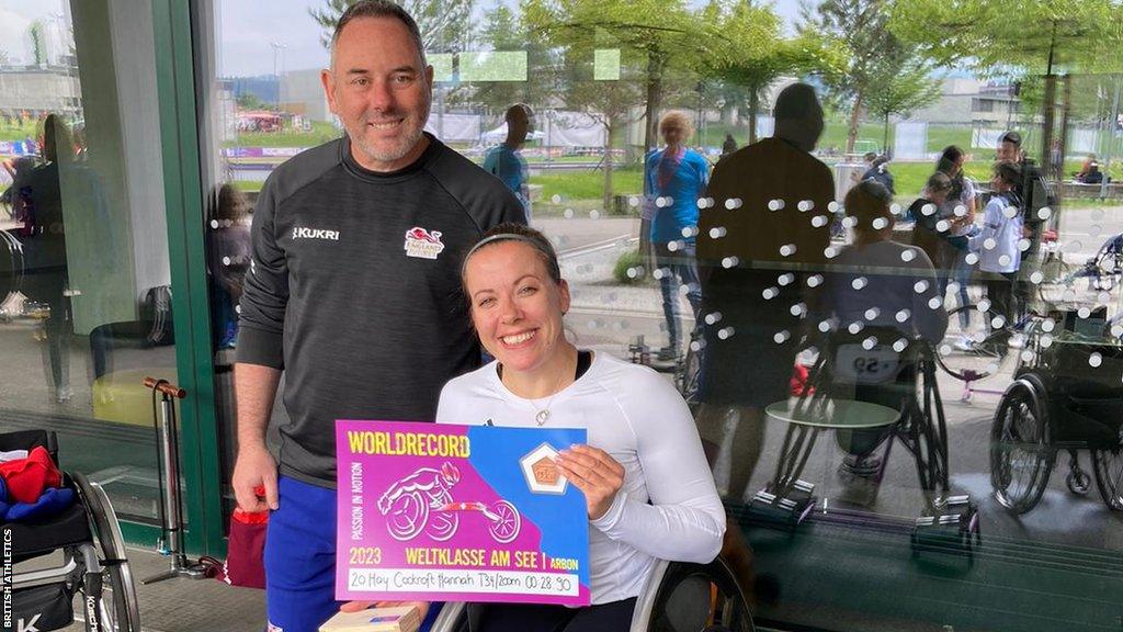 Hannah Cockroft holding a certificate, marking her world record in the T34 200m at Arbon in Switzerland, with her coach Paul Moseley