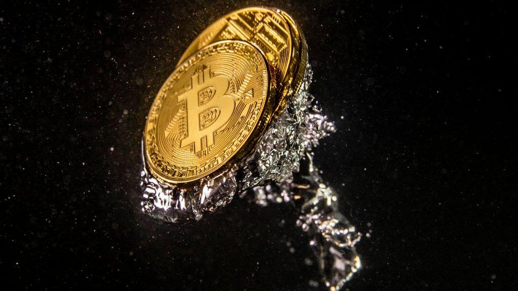 A stock image of coins bearing the bitcoin logo - an illustrative reification of the cryptocurrency - dropped into water