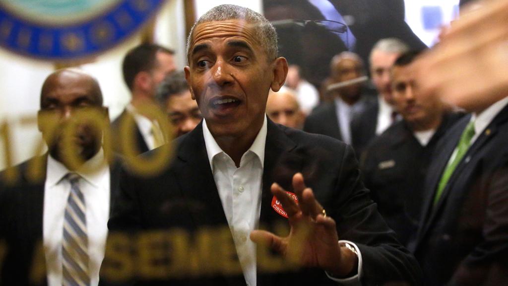 Former President Barack Obama waves to a crowd of people as he attends Cook County jury duty