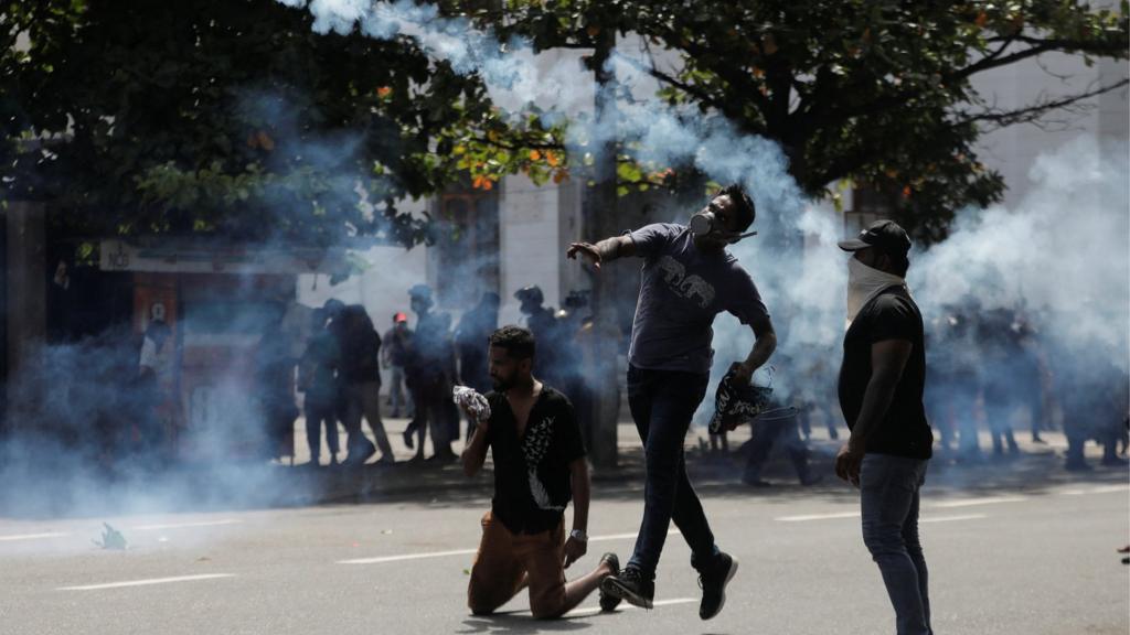 A demonstrator throws back a tear gas grenade towards police members as police use tear gas and water cannons to disperse demonstrators during a protest demanding the resignation of President Gotabaya Rajapaksa, amid the country's economic crisis, near the president's residence in Colombo, Sri Lanka, July 9, 2022. REUTERS/Dinuka Liyanawatte