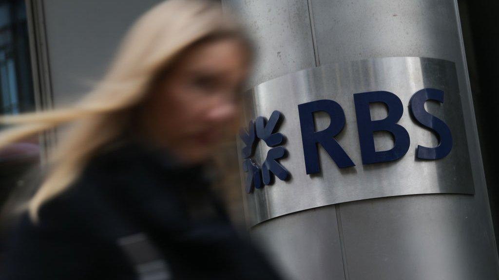 Pedestrian walks past a branch of RBS