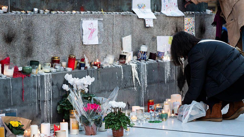A photograph taken on November 11, 2025 shows candles and flowers displayed at a makeshift memorial in tribute of the victims of Paris attacks of November 13, 2015, on the place de la Republique, in Paris