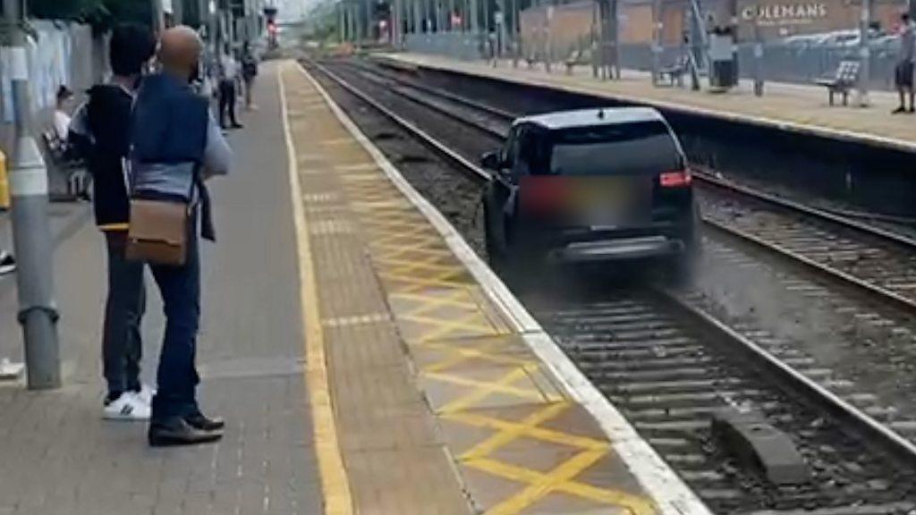 Train station passengers witness the car being driven along the railway line before being abandoned.