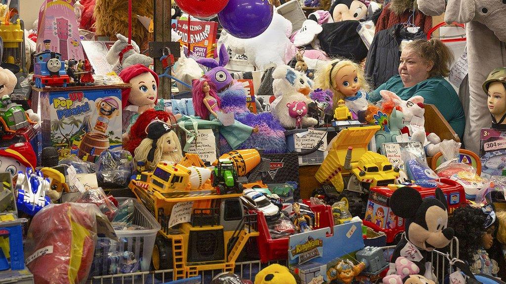 A stall with lots of children's toys with a woman sitting in the corner