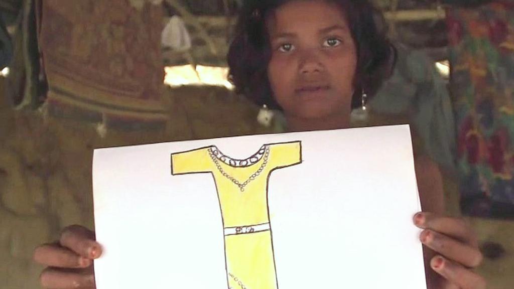 A girl holding up a picture of a dress she left behind.