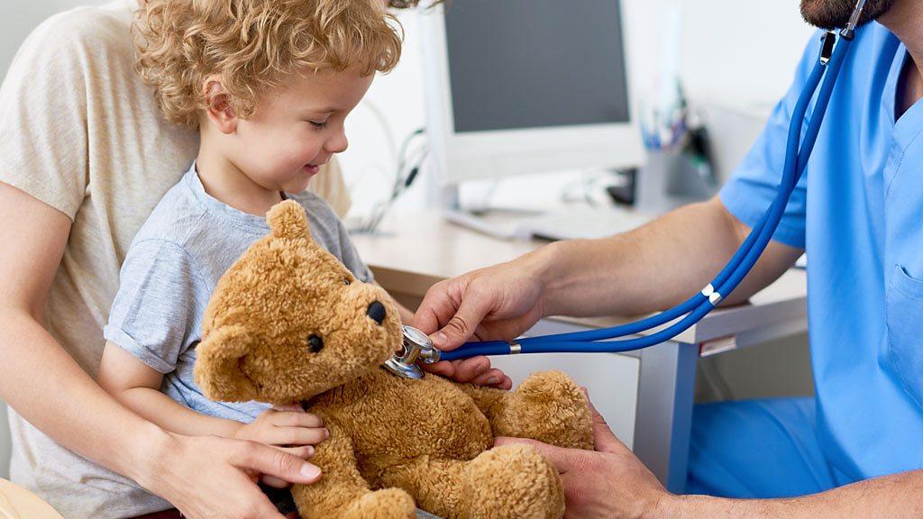 A doctor puts a stethoscope on a child's teddy bear