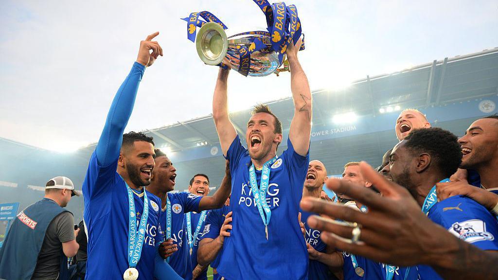 Christian Fuchs of Leicester City lifts the Premier League Trophy as players and staffs celebrate