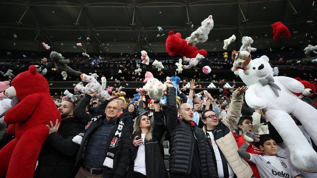 Fans of Besiktas throw Teddy bears onto the field in support for the earthquake victim children