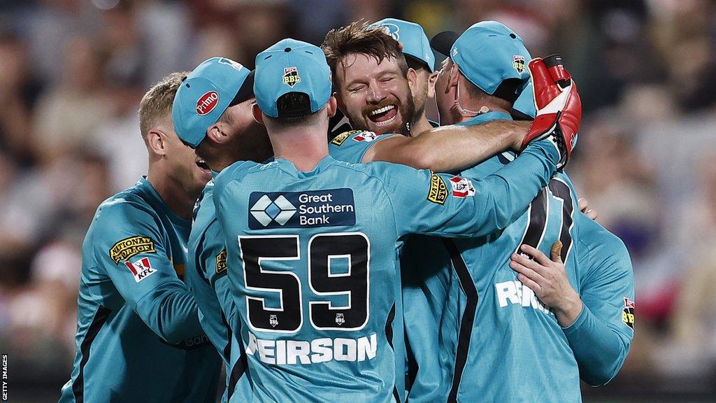 Brisbane Heat players mob Michael Neser after he took a hat-trick against Melbourne Renegades