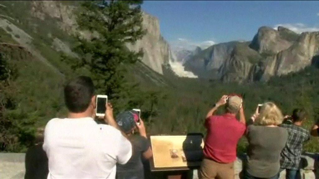 Tourists photograph a rockfall at Yosemite national park