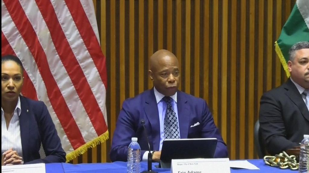 Mayor Eric Adams sits at a panel during a press conference in New York, flanked by NYPD representatives