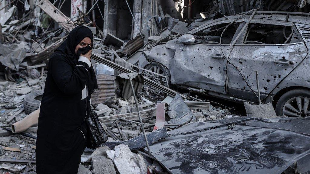 A woman passes by the debris of destroyed buildings as Israeli attacks continue at Al-Shati refugee camp of Gaza City, Gaza on 31 October 2023