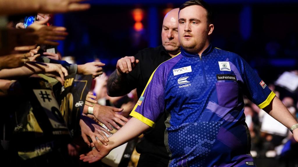 Luke Littler walks to the stage before a Premier League match