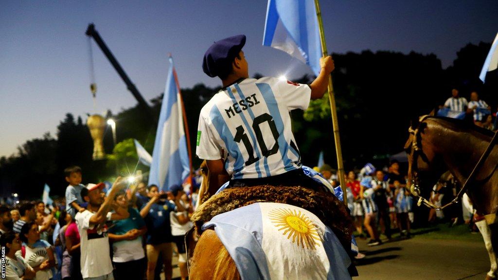 A man on a horse with an Argentina flag and a Messi shirt