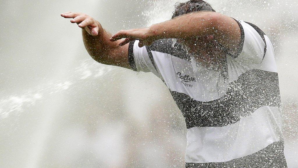 Carl Hayman takes the full force of the sprinklers at the Olympic Stadium